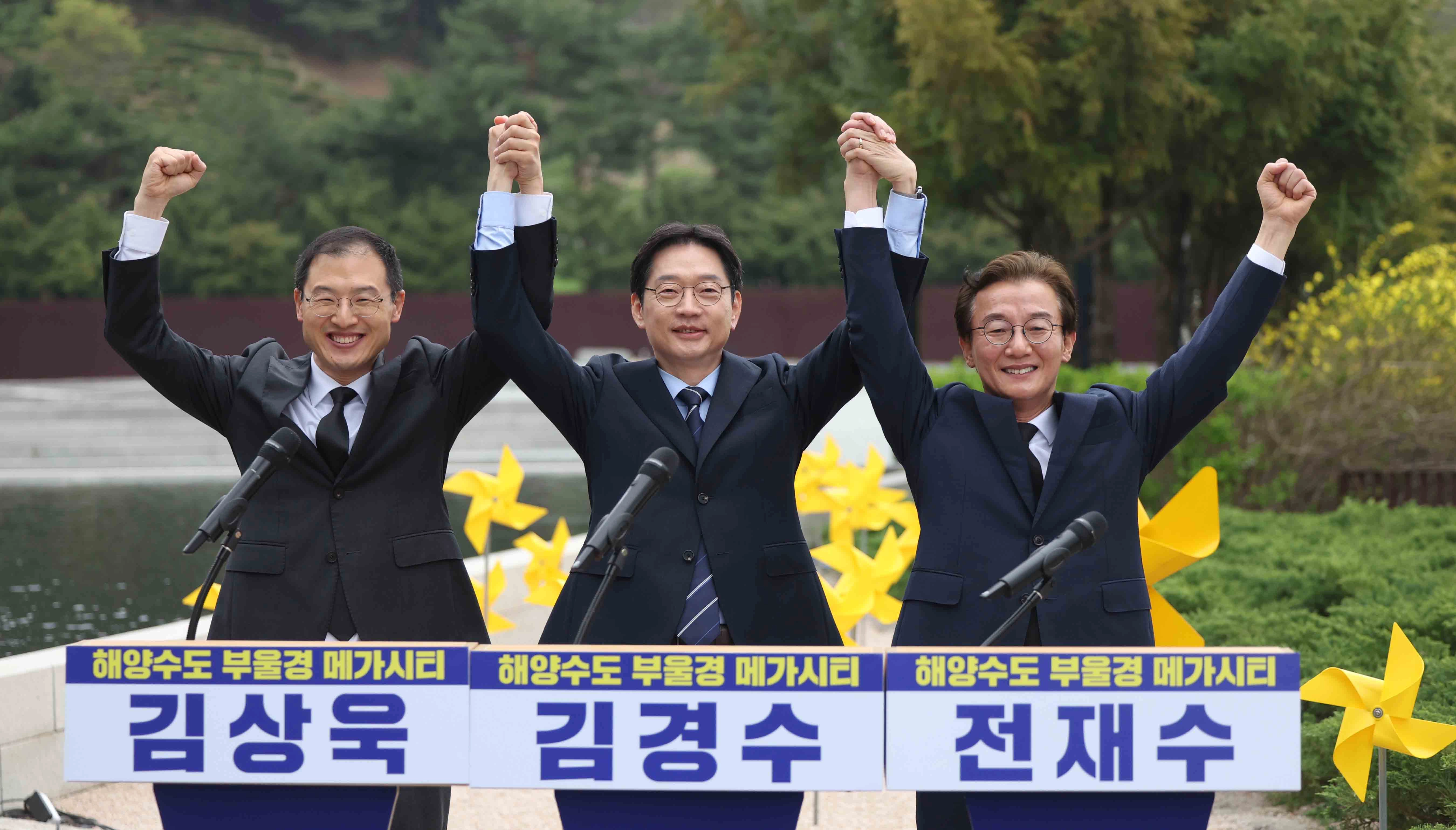 더불어민주당 부울경(부산·울산·경남) 시장·도지사 후보가 14일 오전 경남 김해시 진영읍 봉하마을에서 열린 '해양수도 부울경 메가시티 공동출정식'에서 취재진 요청에 손을 번쩍 들고 인사하고 있다. 왼쪽부터 김상욱 울산시장 후보, 김경수 경남지사 후보, 전재수 부산시장 후보. 2026.4.14